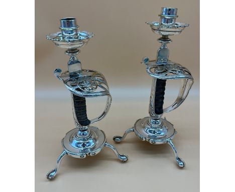 A Pair of VR Stamped British army sword handle candlesticks. Supported by spurs. [30.5cm high] 