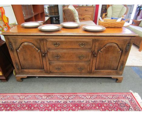 An oak sideboard, three single drawers flanked by cupboard doors on bracket feet, 167cm long x 78cm high x 50cm deep