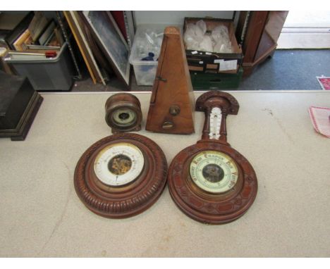 A metronome and three aneroid barometers, two in carved walnut cases 