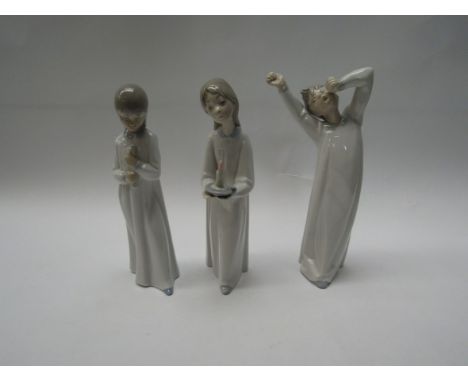 A Lladro figurine girl with candle model No. 4868, Lladro boy stretching and yawning model No. 4870 and a Nao figurine of a y