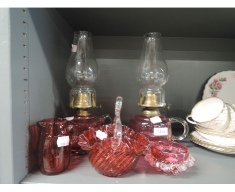 A selection of cranberry glass wares including oil lamp pairCRACK TO BASKET, SMALL NIBBLES ON TOP OF JUG, 2 CHIPS TO GLASS FO