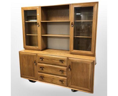 An Ercol elm display cabinet fitted with cupboards and drawers beneath, 155 cm x 44 cm x 162 cm.