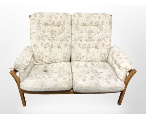 An Ercol stained elm three piece lounge suite in floral upholstery, settee 133 cm wide (requires re-upholstery) 