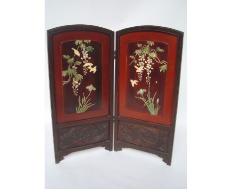 An early 20th Century Chinese hardwood and lacquer two fold firescreen, each arched panel inlaid with carved painted ivory bi