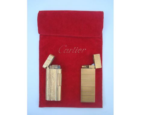 A Cartier gilt metail gas lighter, serial no 71833E and a Dunhill gilt textured bark effect roller lighter (2). 