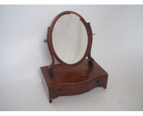 A George III mahogany swing toilet mirror, the oval mirror raised on shaped uprights above a serpentine fronted base with sin