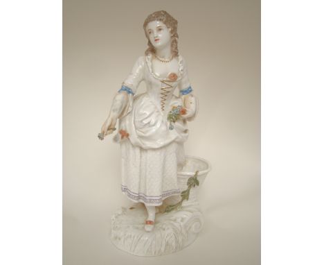 A late 19th Century Copeland porcelain figure of a maiden in 18th Century dress, holding picked flowers and standing next to 