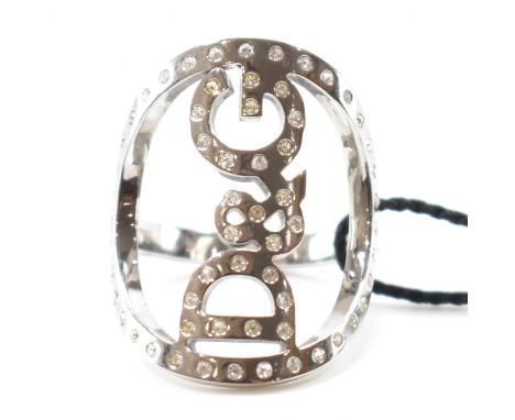 A Dolce and Gabbana jewels white metal designer ring. The ring having a pierced D&amp;G to the head set with white stones. Co