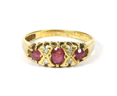 A three stone ruby ring, the central oval faceted ruby flanked on each side by two small circular faceted diamonds and a circ
