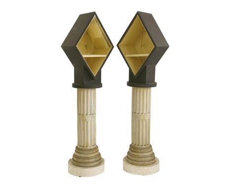 A pair of large display cabinets, each of lozenge form mounted atop a column, each fitted with a light, 170cm high (2)
