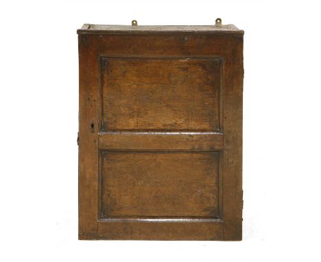 A small oak cupboard, 18th century, with a single two-panelled door opening to reveal a shelf within, 48cm wide, 28cm deep, 6