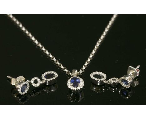 A white gold, sapphire and diamond cluster pendant necklace and earring matched suite, with an oval mixed cut sapphire claw s