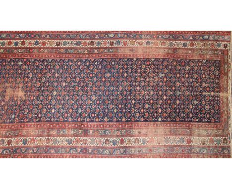A Persian rug, the central panel with a grid of geometric designs on a dark blue ground within multiple borders with geometri
