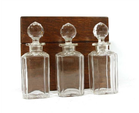 An early 19th century oak decanter box, containing three decanters possibly by Army and Navy ( one decanter chipped )