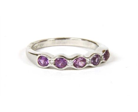 An 18ct white gold sapphire and diamond half eternity ring, with a series of violet pink circular mixed cut sapphires, with a