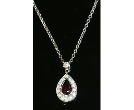 An 18ct white gold, ruby and diamond cluster pendant, with a pear cut ruby, rub set to the centre. A border of brilliant cut 
