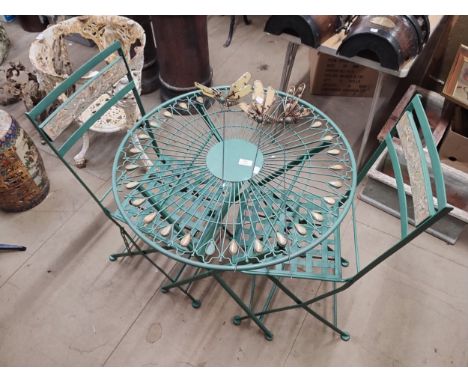 A metal garden table and two chairs and three dragonfly garden ornaments 