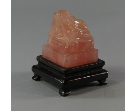 A Chinese rose quartz seal, 19th/20th century, carved to the top with a lion or dog, with seal script inscription, on a woode