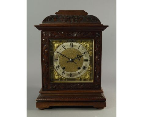 An Edwardian walnut mantel clock, the case carved overall with foliage and panels of flowers, on a stepped base, the brass di