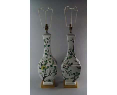 A pair of porcelain lamp bases, 20th century, of square form, painted with flowering trees, on gilt metal bases, 60cm includi