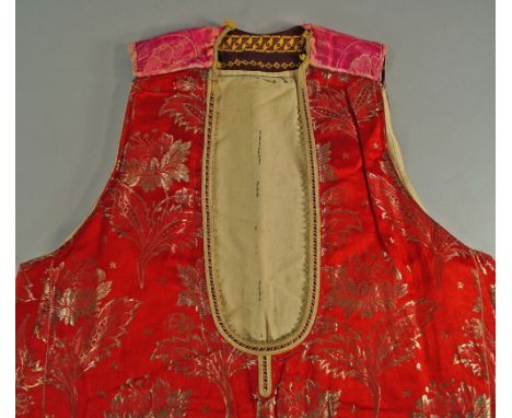 An Indian sleeveless robe, early 20th century, in red silk woven with gold thread, together with a further sleeveless robe, a