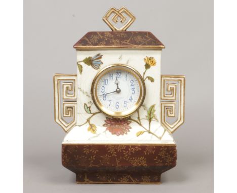 A Wedgwood Aesthetic movement mantel clock. With open fret twin handles, brown glazed borders and painted with flowers. Housi