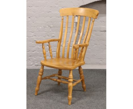 A hardwood slat back arm chair raised on turned supports.