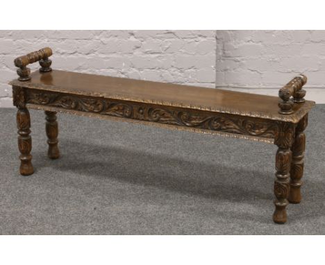 A Victorian Gothic revival carved oak hall bench with turned bolster handles, H 55cm L 131cm D 29cm.