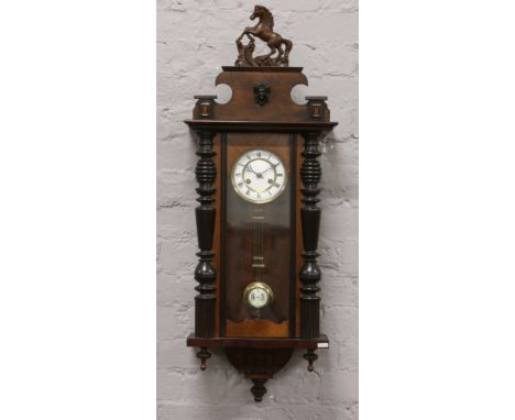 A mahogany Vienna wall clock housing a two train movement, striking on a coiled gong, with key and pendulum.