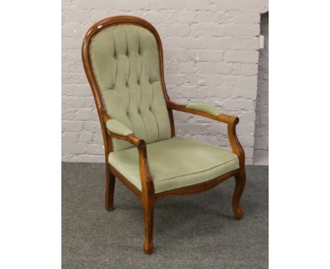 A modern mahogany armchair with deep button upholstery.