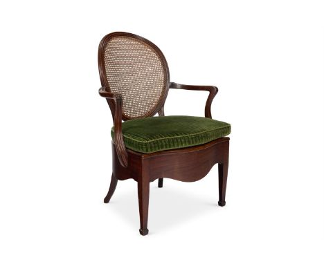 A GEORGE III MAHOGANY AND CANED COMMODE ARMCHAIR  CIRCA 1780  With an oval back, serpentine seat with loose cushion and squar