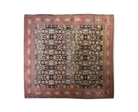 AN AGRA CARPET With an all over design of leaves and palmettes on a black ground within red ground borders, with a heraldic c