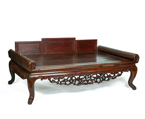 A LARGE CARVED HARDWOOD DAYBED
With scroll arms and stepped backrest, with carved and pierced apron on cabriole supports

All