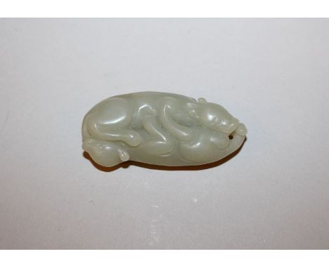 A CHINESE CELADON JADE-LIKE GROUP OF TWO MYTHICAL CREATURES, of hound-like form, 2.6in long.