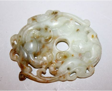 A CHINESE PIERCED JADE-LIKE CARVING OF TWO CONFRONTING DRAGONS, the predominantly celadon green stone with russet inclusions,