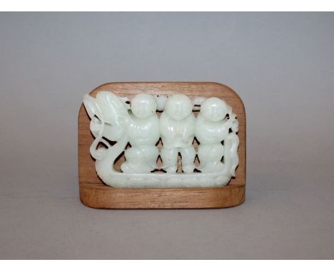 AN EARLY 20TH CENTURY CHINESE CELADON JADE CARVING OF THREE BOYS IN A DRAGON BOAT, together with a fitted wood stand, the thr