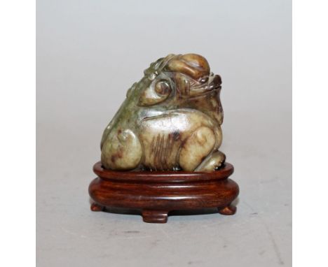 A SMALL 19TH/20TH CENTURY CHINESE JADE-LIKE CARVING OF A SEATED BUDDHISTIC LION, together with a fitted wood stand, the stone