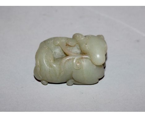 A CHINESE CELADON JADE-LIKE MODEL OF TWO RAMS, one of them with a spray of lingzhi clasped in its mouth, 2.1in wide.