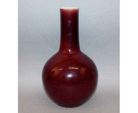 A LARGE CHINESE SANG-DE-BOEUF PORCELAIN BOTTLE VASE, the lightly streaked glaze thinning at the top rim, 15.8in high.