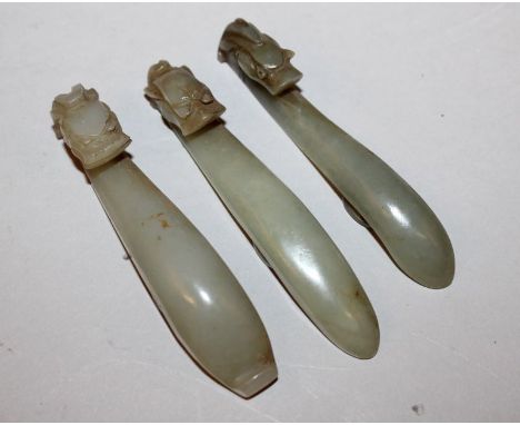 A GROUP OF THREE SIMILAR 19TH CENTURY CHINESE CELADON GREEN JADE BELT HOOKS, each hook carved in the form of a dragons head, 
