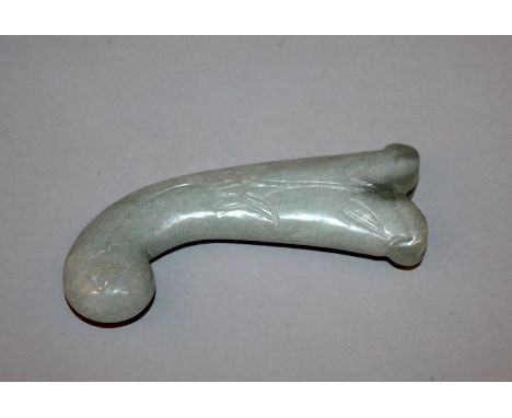 A MUGHAL CELADON JADE-LIKE HANDLE, of curving form, each side carved with a foliate spray, 5.75in long.