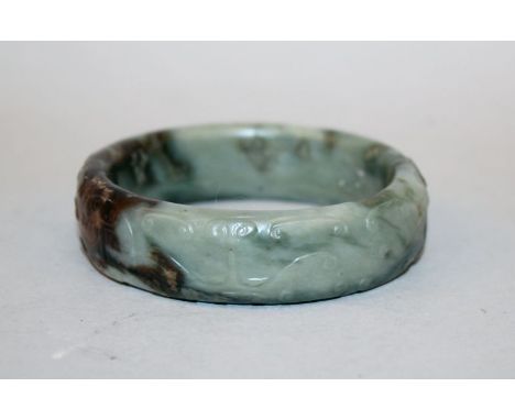 ANOTHER UNUSUAL CHINESE JADE BANGLE, 19th Century or earlier, the stone of predominantly striated celadon tone with dark russ