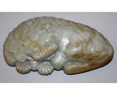 A LARGE CHINESE JADE CARVING OF A BUDDHISTIC LION, the mythical creature lying down, the stone of predominantly celadon green