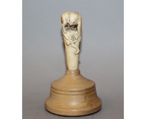 A GOOD QUALITY JAPANESE MEIJI PERIOD CARVED IVORY CANE HANDLE, mounted on a wood stand, the handle carved in the form of a bi