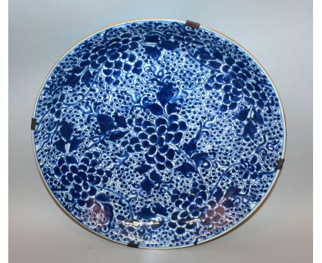 A LARGE CHINESE KANGXI PERIOD BLUE & WHITE PORCELAIN DISH, of saucer shape, the interior painted with dense foliage and peony
