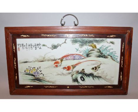 A CHINESE HARDWOOD FRAMED PORCELAIN PANEL, decorated with pheasants and other birds in a garden setting, the frame 24in x 13.