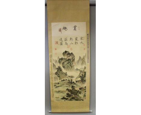 A 20TH CENTURY CHINESE HANGING SCROLL PAINTING ON SILK, depicting a mountainous river landscape scene, on a patterned silk mo