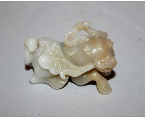 A CHINESE JADE-LIKE MODEL OF A WATER BUFFALO, clasping a spray of lingzhi in its mouth, 2.5in long.