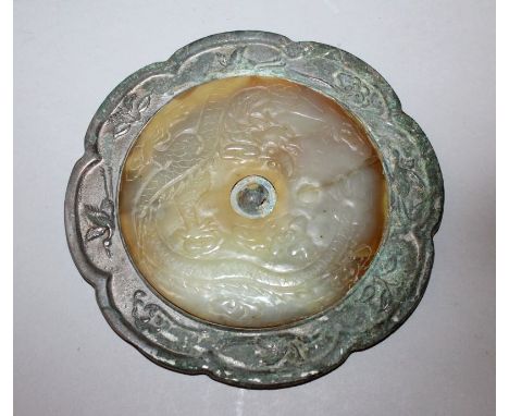 A CHINESE TANG STYLE SILVERED BRONZE MIRROR WITH A CIRCULAR JADE INSET, the jade carved in shallow relief with a dragon amids