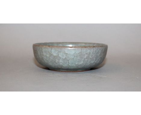 A CHINESE CELADON PORCELAIN BOWL, applied with a mottled and crackled glaze, 4.3in diameter.